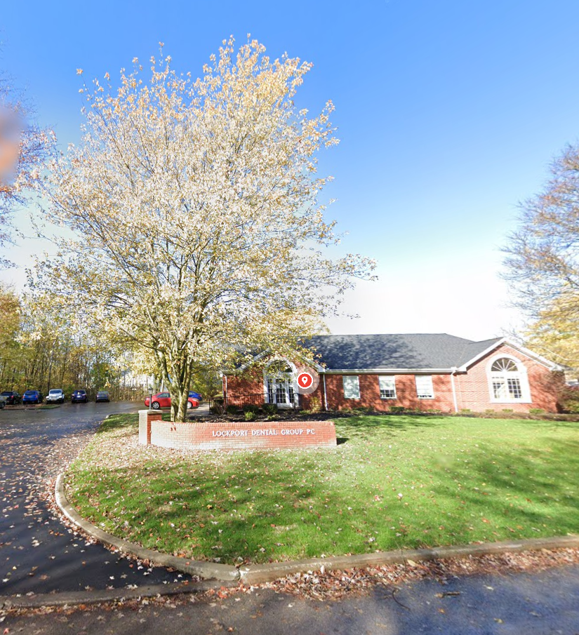 Lockport Dental Group brick building with blooming tree and entrance sign in spring.