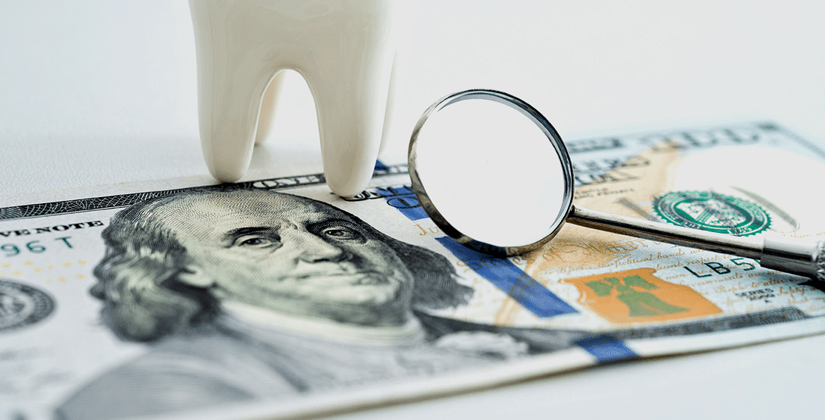 Dental mirror and tooth model on US currency symbolizing dental costs and financial planning for dental care.
