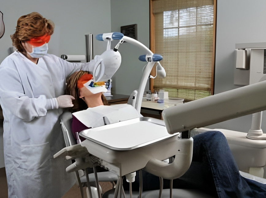 Dental hygienist applying protective eyewear to patient in modern dental treatment room.