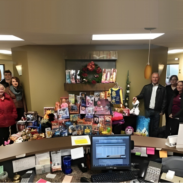 Dental office staff gathered around toy donation collection display during charity event.